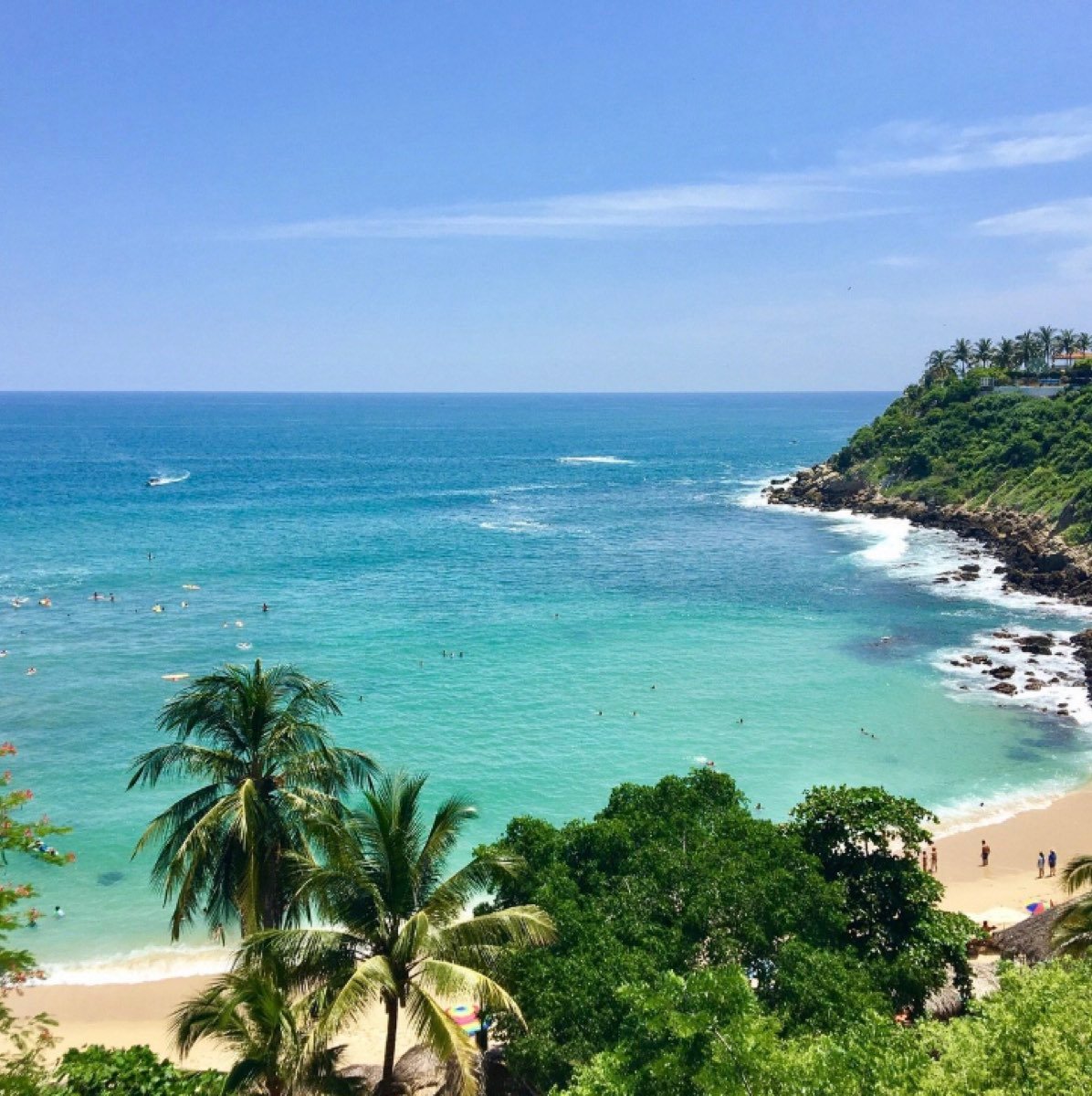 An elevated view of a turquoise bay lined with palms, Puerto Escondido.