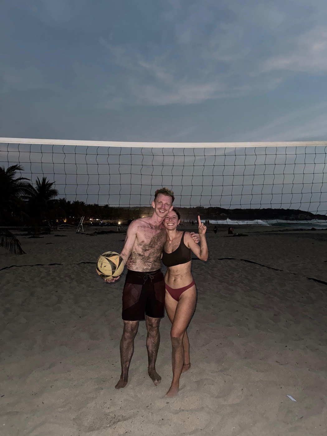Two players celebrating together on the beach at dusk after the tournament.