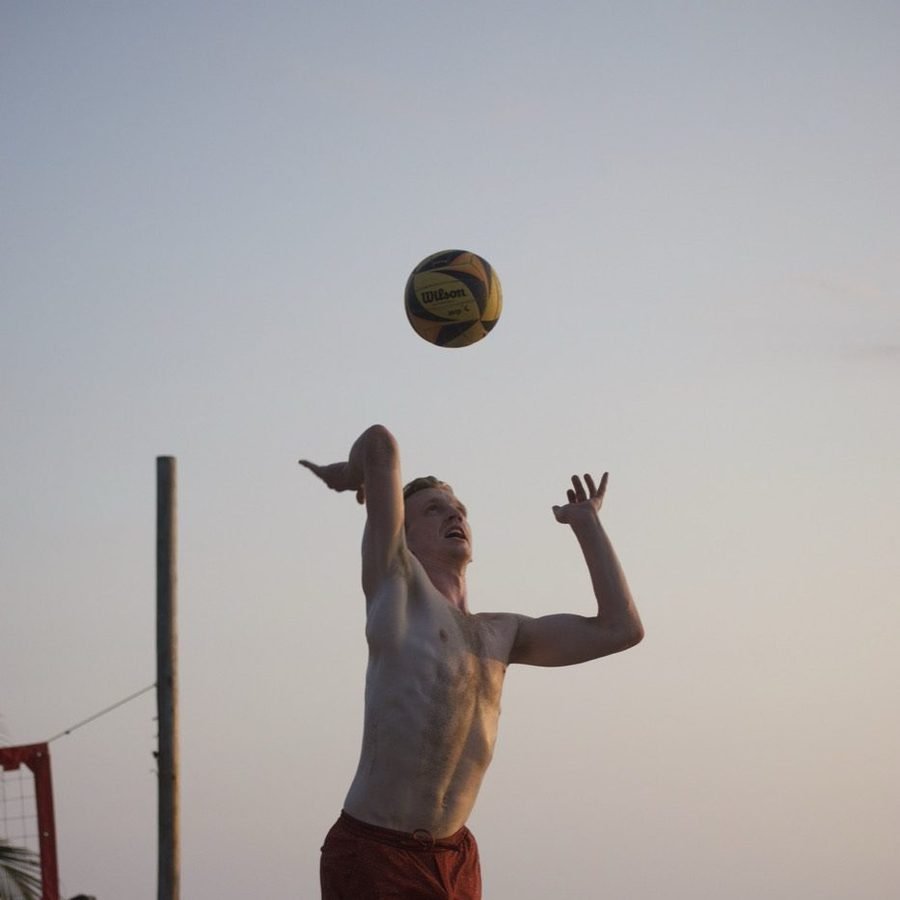 A player jumping to spike against a bright sky.